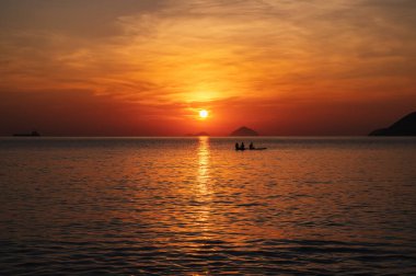 Silhouettes of people floating on sap boards in the sea in the morning at sunrise in summer clipart