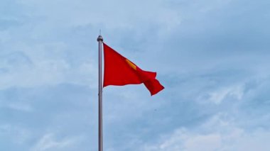 Bayrak direğindeki Vietnam bayrağı bulutlu bir gökyüzüne karşı rüzgarda dalgalanıyor.