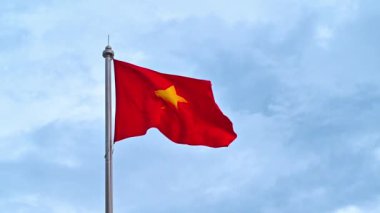 Bayrak direğindeki Vietnam bayrağı bulutlu bir gökyüzüne karşı rüzgarda dalgalanıyor. Yavaş çekim