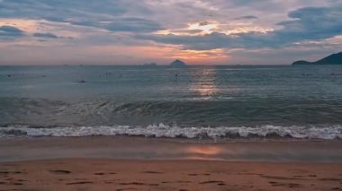 Deniz kenarındaki kumsalda yazın gün doğumunda dalgalarla birlikte Asya 'da tropik bir tatil köyünde.