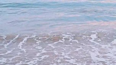 Yazın kumlu bir sahilde deniz dalgaları.