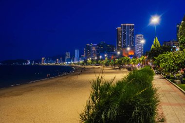 Gece gökdelenler ve oteller manzaralı, deniz kenarında kumlu bir sahil. Vietnam 'daki Nha Trang şehrinin panoraması