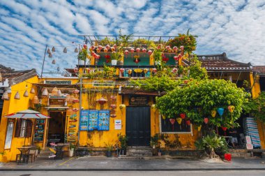 Vietnam 'ın Hoi An şehrindeki eski kasabanın sokaklarındaki geleneksel sarı bir evin ön cephesi. Hoi An, Vietnam - 12 Eylül 2024
