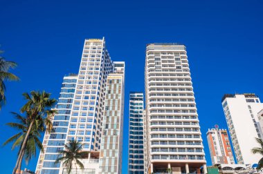 Uzun modern gökdelenler otelleri Vietnam 'da mavi gökyüzüne karşı Asya' da bir tatil köyünde. Nha Trang, Vietnam - 13 Ağustos 2024