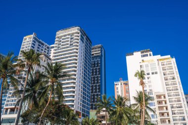Arka planda modern gökdelen otelleri yazın Vietnam 'da bir tatil köyünde mavi gökyüzü. Nha Trang, Vietnam - 13 Ağustos 2024