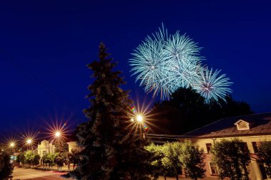 Arka planda, gece gökyüzünde havai fişekler. Renkli selamlama patlamaları