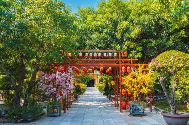 Çin fenerleriyle süslenmiş kapı, Vietnam 'da Asya' da Budist Pagoda 'daki bir bahçeye ağaçlarla park etmek için.