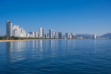 Vietnam 'ın Nha Trang tatil köyünün panoramik manzarası. Deniz kenarında kumlu bir plajı ve otellerin gökdelenleri var.