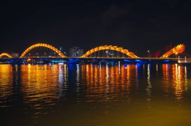 Han Nehri üzerindeki Ejderha Köprüsü, Vietnam 'ın Da Nang şehrinde geceleri altın ışıklarıyla ünlü bir simgedir.