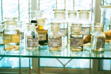 Gizli bir biyokimya laboratuvarının rafında numunelerle dolu şişeler ve test tüpleri.