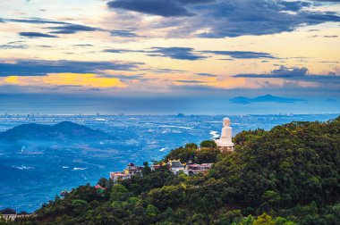 Top view of Da Nang city and Buddha statue from a mountain in the Ba Na Hills in Vietnam at sunset clipart