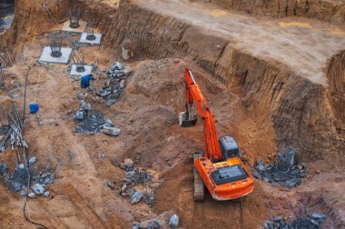 Kazıcı, bir inşaat alanının temelinin altındaki zemini kazıyor.