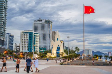 The flag of Vietnam on the flagpole and the Lotus Tower on the central square in Nha Trang city. Nha Trang, Vietnam - September 6, 2024 clipart