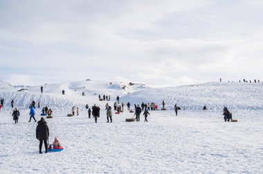 İnsanlar kış aylarında karla kaplı dağlarda aktif bir eğlence için borularda yokuş aşağı gidiyorlar. Şymkent, Kazakistan - 27 Ocak 2024