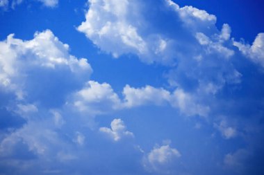 Beyaz tüylü kümülüs bulutlarıyla mavi gökyüzünün arka planı