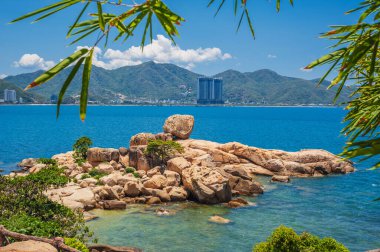 Nha Trang, Vietnam 'daki plajların, dağların ve yüksek binaların arka planında büyük kayalar var.