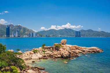 Nha Trang, Vietnam 'daki plajların, dağların ve yüksek binaların arka planında büyük kayalar var.