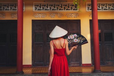 Vietnam 'daki bir pagoda tapınağında hayranı olan Non La şapkalı Vietnamlı bir turist kadının Asya seyahatine çıkması.