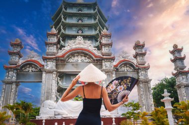 Vietnam 'daki Da Nang pagoda' da Vietnamlı Non La şapkalı bir kadın turistin arkasında. Asya 'da seyahat ve turizm