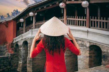 Vietnam 'da Hoi An' da eski bir kasabada Vietnam 'da eski bir Japon köprüsünde Vietnamlı şapkalı bir kız gezgin kızın arkası.