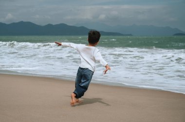 Tatilde deniz kenarında koşan mutlu bir çocuğun sırtında.
