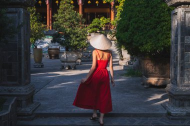 Vietnam 'da bir pagoda' da, geleneksel Vietnam şapkalı genç bir turistin arkasında.