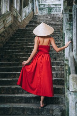 Vietnam 'da bir merdivende şapkasız ve kırmızı elbiseli bir kadının arkasında. Asya 'da seyahat ve turizm