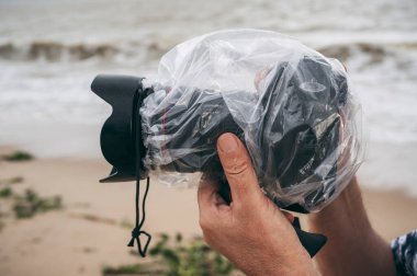 Yağmura karşı koruyan ve yağmurlu bir günde doğaya sıçrayan su geçirmez bir kutuda dijital fotoğraf makinesi.