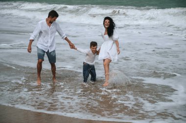 Mutlu bir aile ve oğlu yaz tatilinde sahilde oynuyorlar.