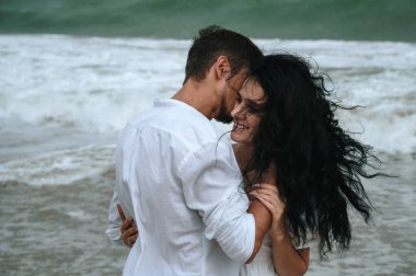 Mutlu, genç ve güzel bir çift. Yaz tatilinde sahilde birbirlerine sarılıyorlar.