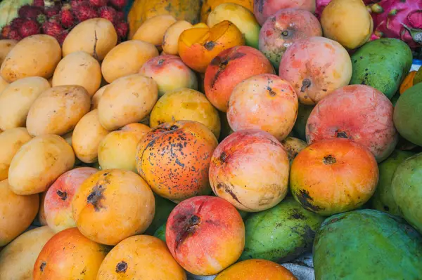 Tayland 'da bir Asya sokak pazarında tezgahın üzerinde taze tropik olgun mango çeşitleri.