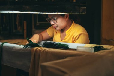 Vietnamlı bir kadın nakışçı, Asya 'nın Hoi An şehrindeki bir atölyede ipek bir tablo işliyor. Hoi An, Vietnam - 1 Aralık 2024