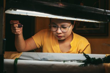Vietnamlı kadın, Asya 'da Hoi An' da bir atölyede ipek nakış işliyor. Hoi An, Vietnam - 1 Aralık 2024