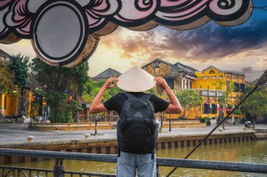 Vietnam 'da, Hoi An' da Vietnam 'da eski bir kasabadaki köprüde Vietnamlı erkek turist şapkası takıyordu.
