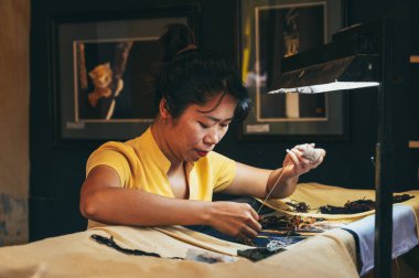 Vietnamlı kadın nakışçı, Vietnam 'ın Vietnam şehrinde Hoi An şehrindeki bir atölyede ipek bir tablo işliyor. Hoi An, Vietnam - 1 Aralık 2024
