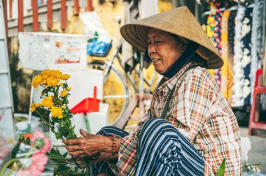 Vietnam 'da Hoi An' da Asya pazarında çiçek satan mutlu, yaşlı Vietnamlı kadın. Hoi An, Vietnam - 1 Aralık 2024