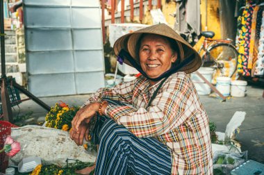 Vietnam 'da Hoi An' da Asya pazarında çiçek satan mutlu, yaşlı Vietnamlı kadın. Hoi An, Vietnam - 1 Aralık 2024