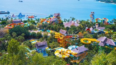 Slaytlı ve yazın tatil köyünde yüzme havuzlu büyük renkli bir su kemeri. Vietnam 'ın Nha Trang kentindeki VinPearl Adası' nda deniz kenarındaki eğlence parkı insansız hava aracından görünüyor.