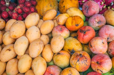 Tayland 'daki Asya sokak pazarının tezgahında çeşitli mango çeşitleri ve taze Asya egzotik meyveler.