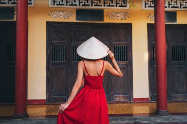 Vietnam 'da bir pagoda' da, geleneksel Vietnam şapkalı güzel bir turistin arkasında.