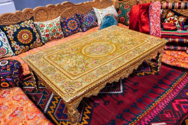 Özbekistan 'da bir evin içinde güzel desenli geleneksel Özbek dastarkhan masası, renkli yastıklar ve kaliteli bir halı. Orta Asya 'nın yaşam ve kültürü