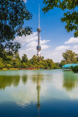Özbekistan 'ın Taşkent kentindeki yüksek televizyon kulesi gölet suyunda yansıması olan mavi bir gökyüzünün arka planına karşı.