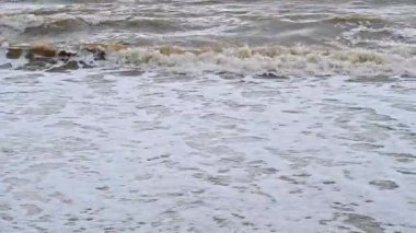 Kışın muson mevsiminde kumlu sahildeki fırtınada denizde kirli büyük dalgalar