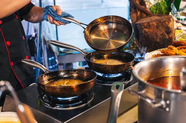Erkek aşçı bir restoranın mutfağında yemek hazırlar. Fırında tavayla yemek pişirir.