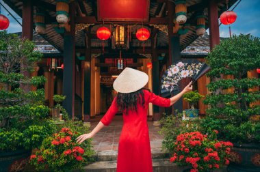 Vietnam 'da Vietnam' da Budist tapınağında Vietnam konisi şapkalı bir kadın turistin arkasında.