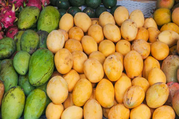 Tayland 'da bir Asya sokak pazarında tezgahın üzerinde taze tropik olgun mango çeşitleri.