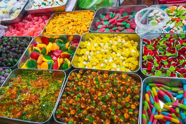 Marketteki tezgahın üzerinde çeşitli renkli, parlak marmelatlar ve çiğnenebilir şekerler var.