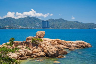 Nha Trang, Vietnam 'daki plajların, dağların ve yüksek binaların arka planında büyük kayalar var.