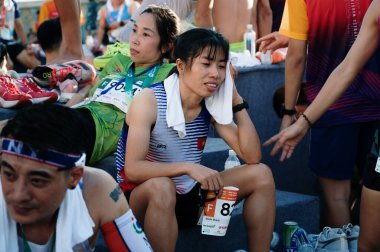 Nha Trang, Khanh Hoa Eyaleti, Vietnam - 11 Ağustos 2024: VnExpress nha trang Maratonu 'nun Asyalı katılımcıları 2024 Yarış sonrası basamaklarda rahatça oturuyorlar.