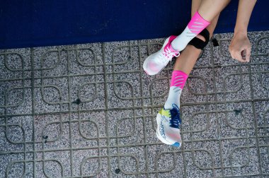 Nha Trang, Khanh Hoa Eyaleti, Vietnam - 11 Ağustos 2024: Esnek ve etkin giyimli kadın ve spor ayakkabıları gri arka planda bacakları esnetiyor, motivasyon